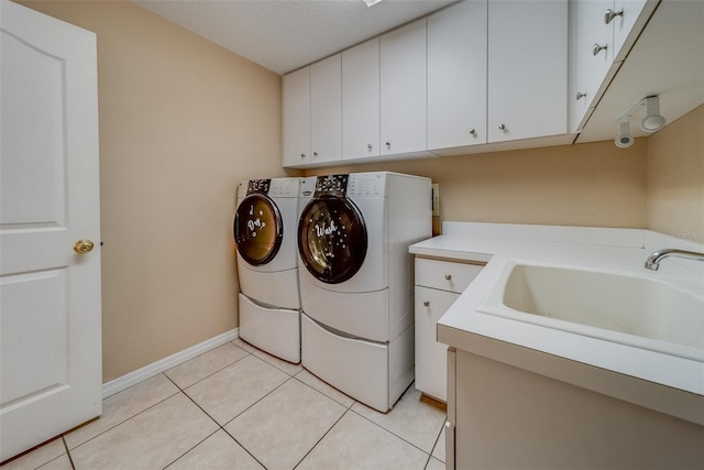 washroom with separate washer and dryer, sink, light tile patterned floors, and cabinets