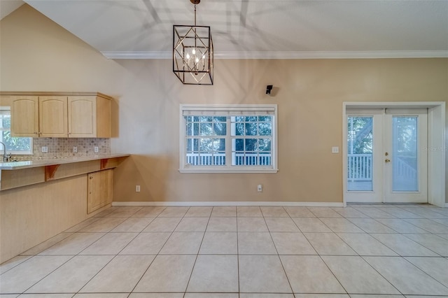 unfurnished dining area with french doors, light tile patterned floors, ornamental molding, and a notable chandelier