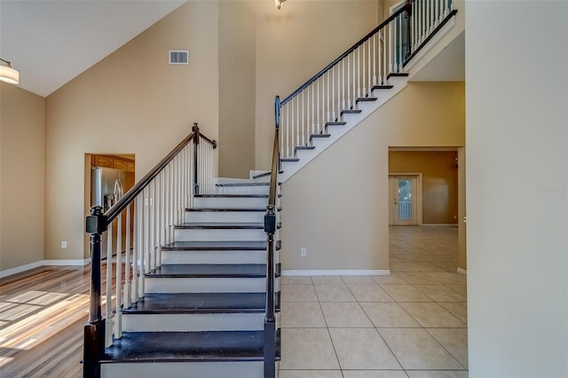 staircase with tile patterned flooring and high vaulted ceiling