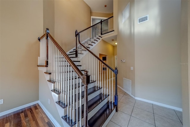 staircase featuring tile patterned flooring and a high ceiling