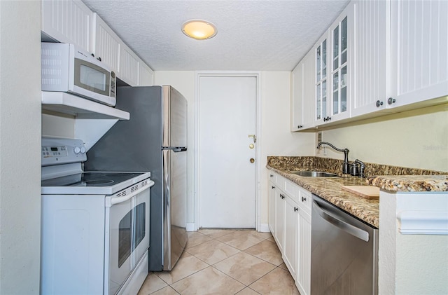 kitchen featuring dishwasher, sink, white cabinets, dark stone counters, and electric stove