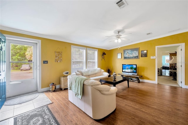 living room with light hardwood / wood-style flooring, ceiling fan, and crown molding