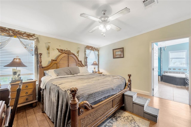 bedroom featuring light wood-type flooring, ensuite bathroom, ceiling fan, crown molding, and multiple windows