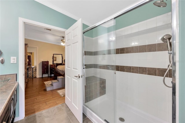 bathroom featuring a shower with door, tile patterned floors, ceiling fan, and ornamental molding