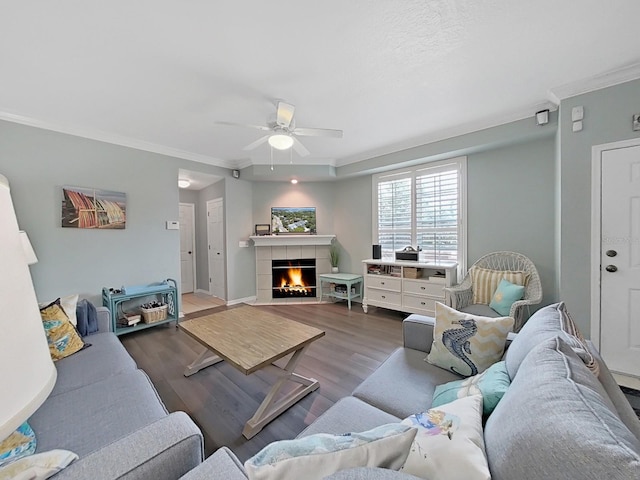 living room featuring a tile fireplace, ceiling fan, ornamental molding, and hardwood / wood-style flooring