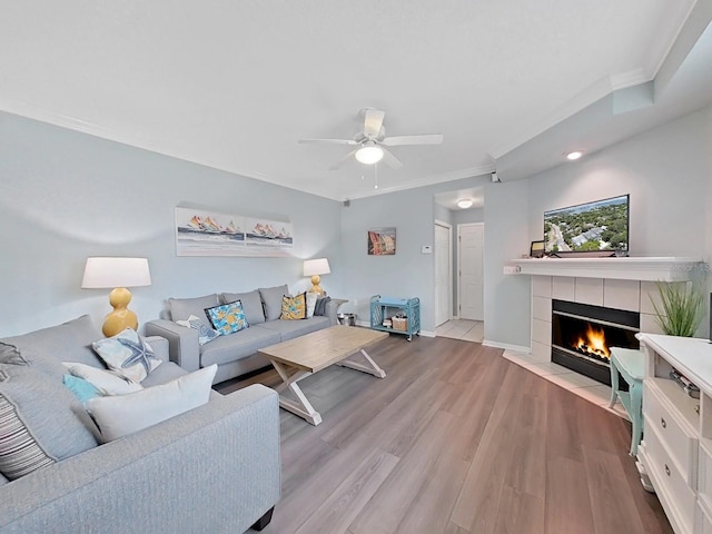 living room featuring a fireplace, light hardwood / wood-style floors, ceiling fan, and ornamental molding