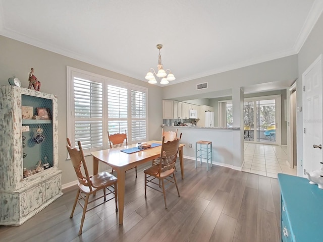 dining space with crown molding, hardwood / wood-style floors, and a notable chandelier