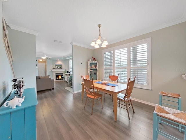 dining area featuring wood-type flooring, ceiling fan with notable chandelier, and ornamental molding