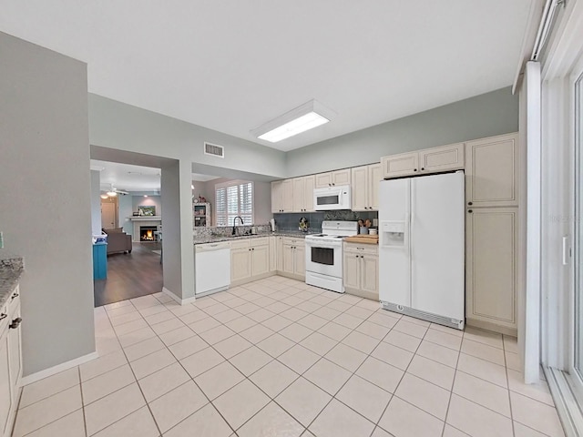 kitchen featuring light tile patterned flooring, decorative backsplash, white appliances, and sink