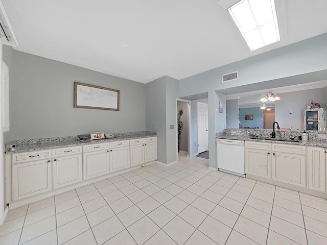 kitchen featuring white dishwasher, sink, light stone countertops, light tile patterned flooring, and a chandelier