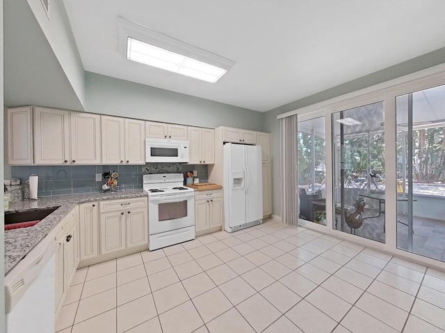 kitchen featuring light stone countertops, sink, backsplash, white appliances, and light tile patterned floors