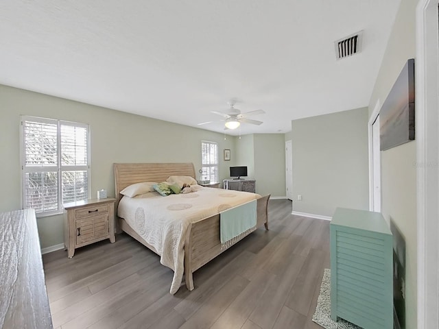 bedroom with multiple windows, ceiling fan, and wood-type flooring