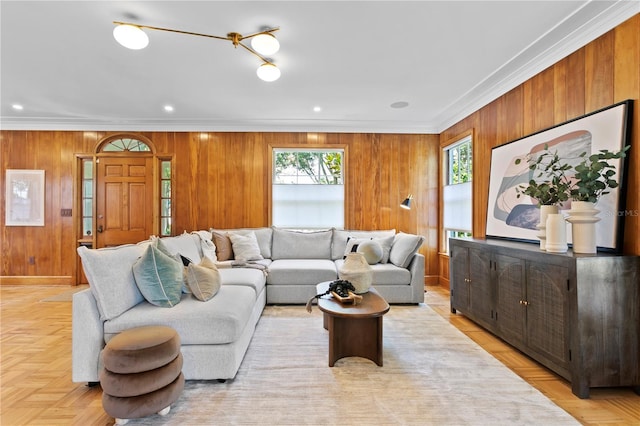 living room with crown molding, light parquet flooring, and wood walls