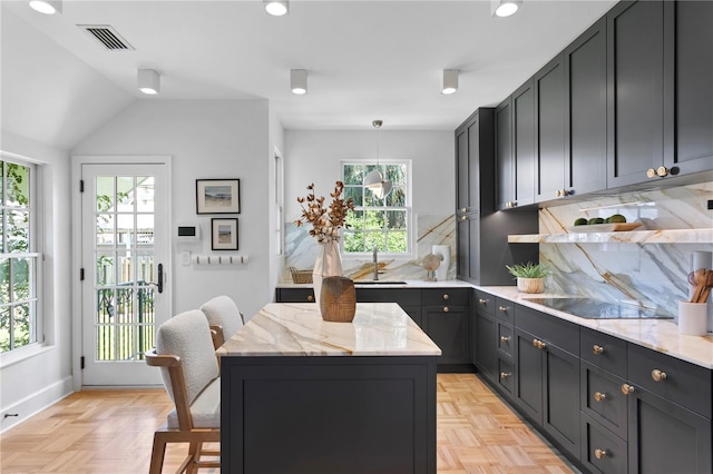 kitchen with light stone countertops, decorative backsplash, black electric cooktop, and decorative light fixtures