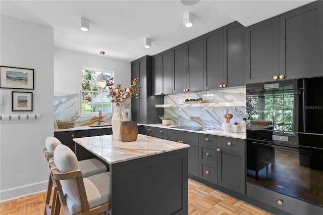 kitchen featuring sink, decorative light fixtures, double oven, light stone countertops, and decorative backsplash