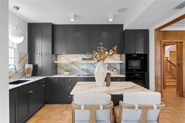 kitchen with pendant lighting, sink, backsplash, light parquet floors, and light stone counters