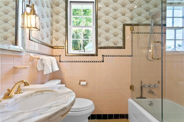 full bathroom featuring tile walls, sink, tiled shower / bath, and toilet