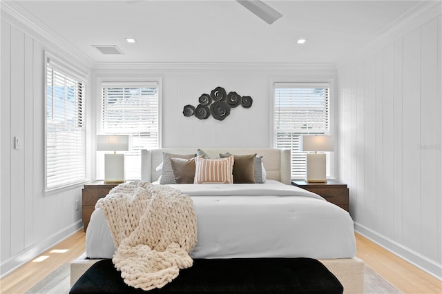 bedroom featuring ornamental molding, light hardwood / wood-style floors, and wood walls