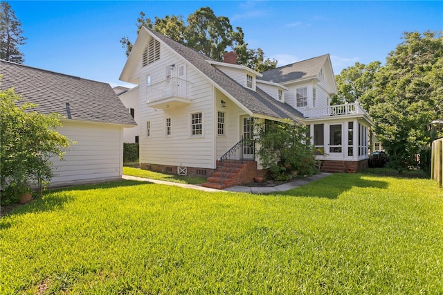 rear view of property with a balcony, a sunroom, and a lawn