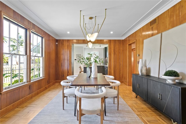 dining room featuring light parquet flooring, ornamental molding, and wooden walls