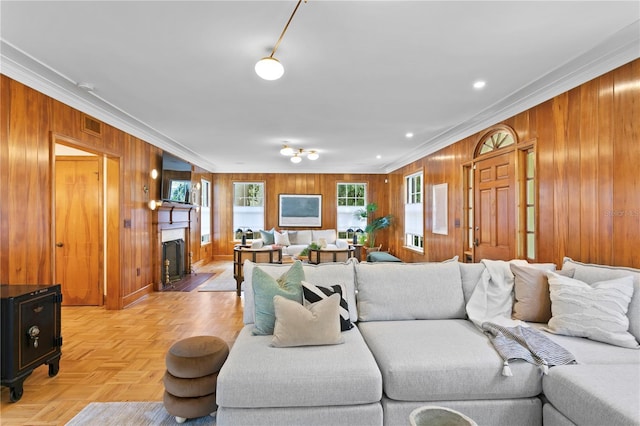 living room with crown molding, wooden walls, and light parquet floors