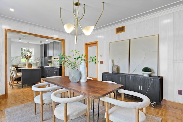 dining area featuring crown molding, light parquet flooring, and a notable chandelier