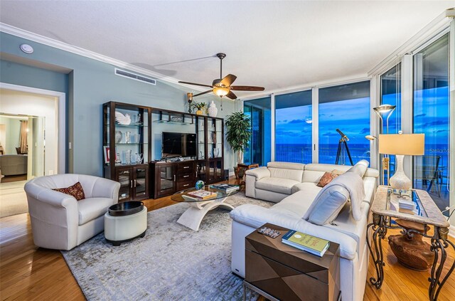 living room featuring hardwood / wood-style flooring, ornamental molding, ceiling fan, and expansive windows