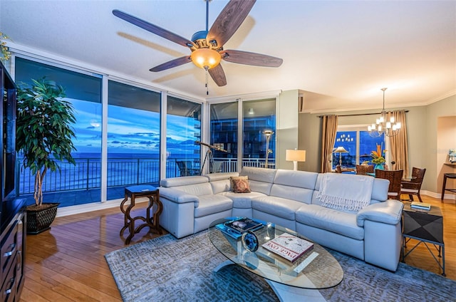 living room with ornamental molding, ceiling fan with notable chandelier, a water view, wood-type flooring, and floor to ceiling windows