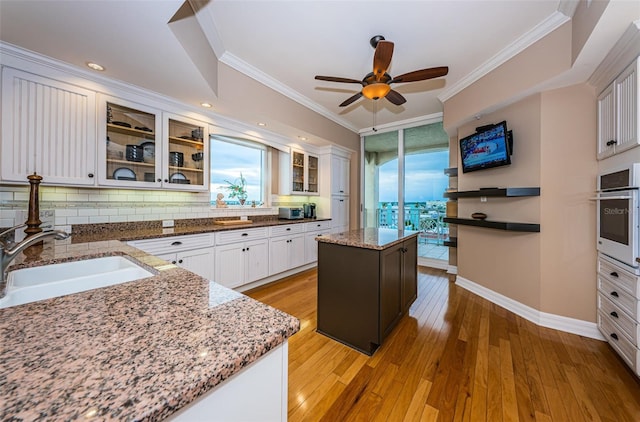 kitchen with oven, a wealth of natural light, light hardwood / wood-style floors, and a kitchen island