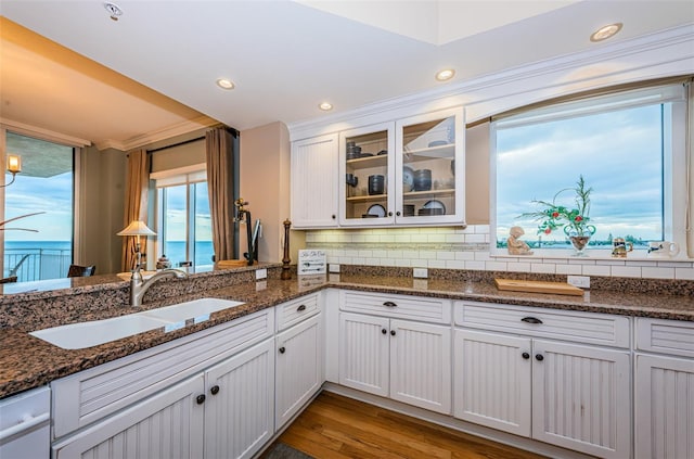 kitchen featuring light hardwood / wood-style floors, white cabinetry, dark stone countertops, sink, and dishwasher