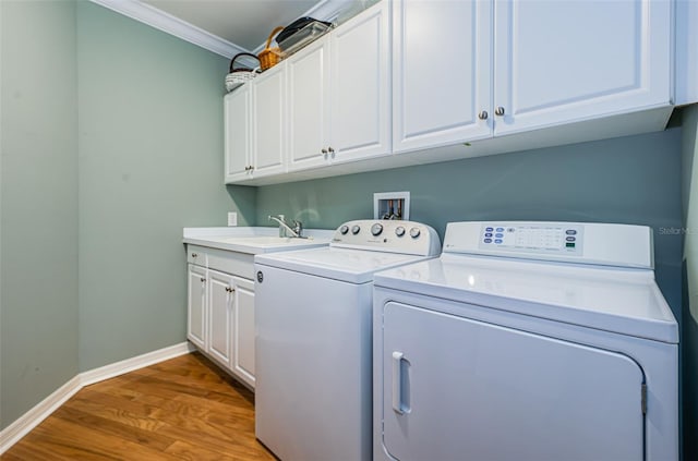 laundry room featuring cabinets, ornamental molding, independent washer and dryer, wood-type flooring, and sink