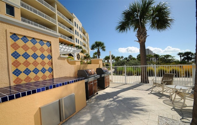 view of patio featuring a pergola, an outdoor kitchen, and a balcony