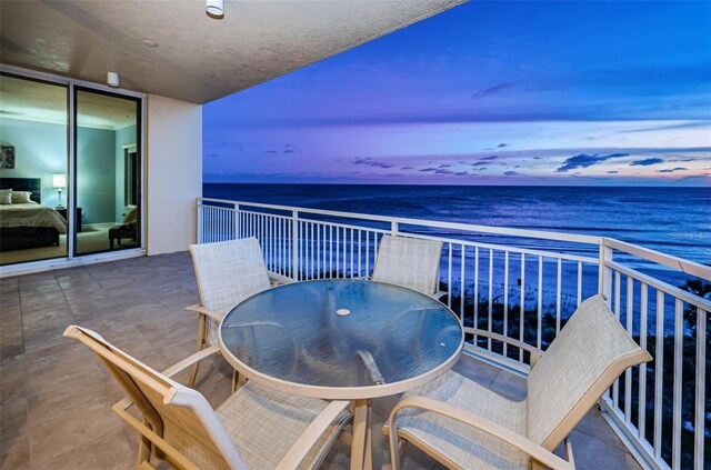 balcony at dusk featuring a water view