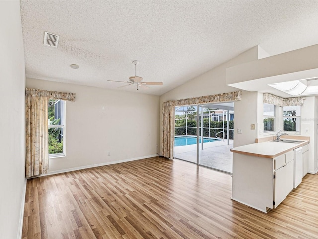 kitchen featuring ceiling fan, sink, light hardwood / wood-style flooring, white cabinetry, and lofted ceiling