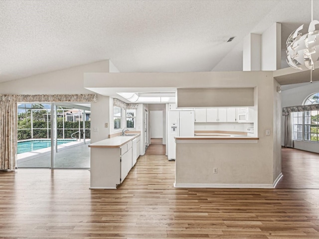 kitchen featuring white cabinets, a healthy amount of sunlight, white appliances, and light wood-type flooring