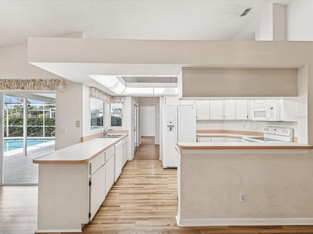 kitchen with white cabinets, white appliances, kitchen peninsula, and sink