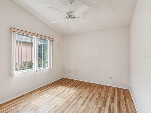 spare room featuring light wood-type flooring, a textured ceiling, ceiling fan, and lofted ceiling