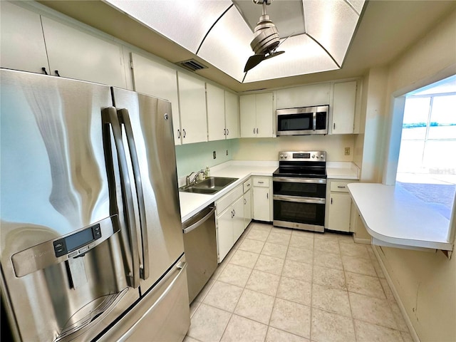 kitchen featuring sink, stainless steel appliances, white cabinetry, and light tile patterned floors