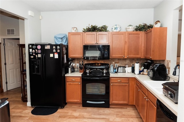 kitchen with decorative backsplash, black appliances, and light hardwood / wood-style floors