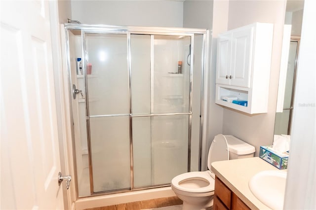 bathroom featuring vanity, a shower with door, wood-type flooring, and toilet