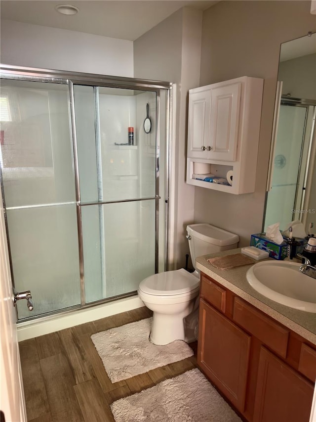 bathroom featuring vanity, an enclosed shower, hardwood / wood-style flooring, and toilet