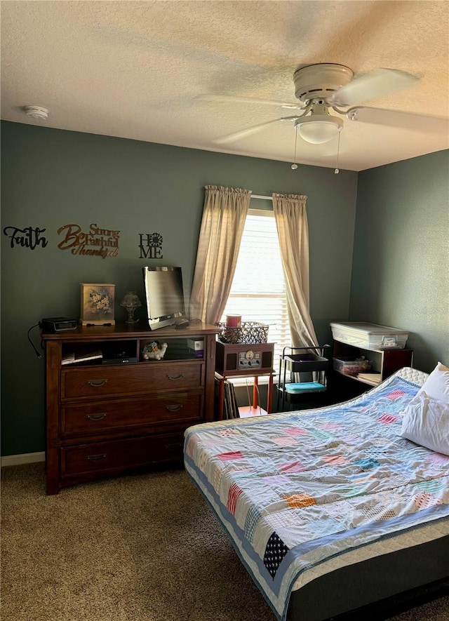 bedroom featuring dark colored carpet, a textured ceiling, and ceiling fan