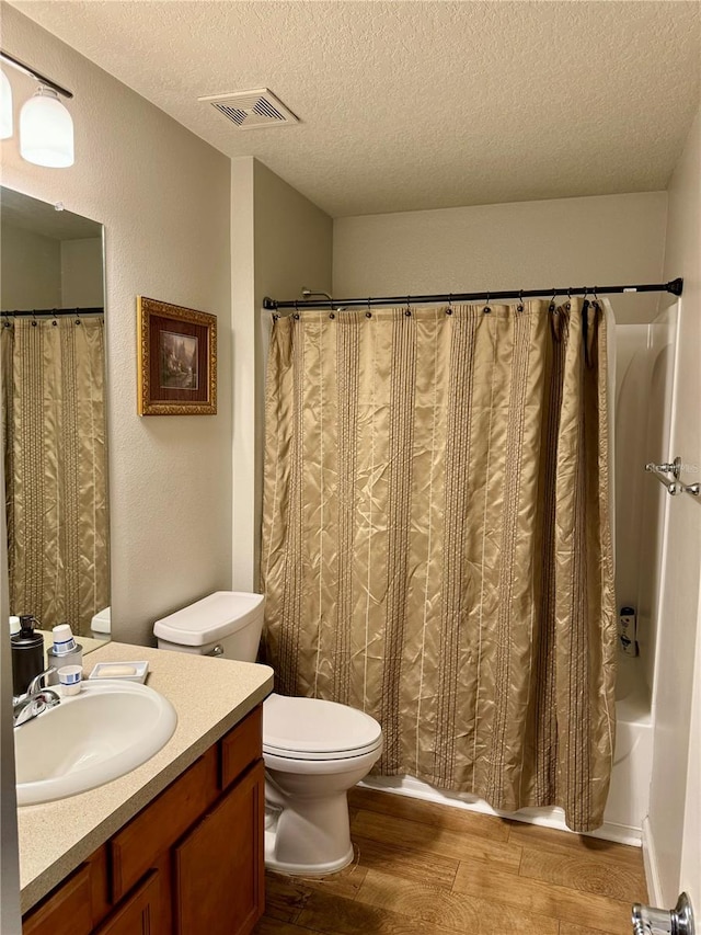 full bathroom with a textured ceiling, toilet, vanity, shower / tub combo with curtain, and hardwood / wood-style flooring