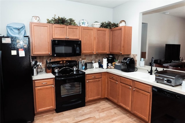 kitchen featuring backsplash, black appliances, light hardwood / wood-style flooring, and sink