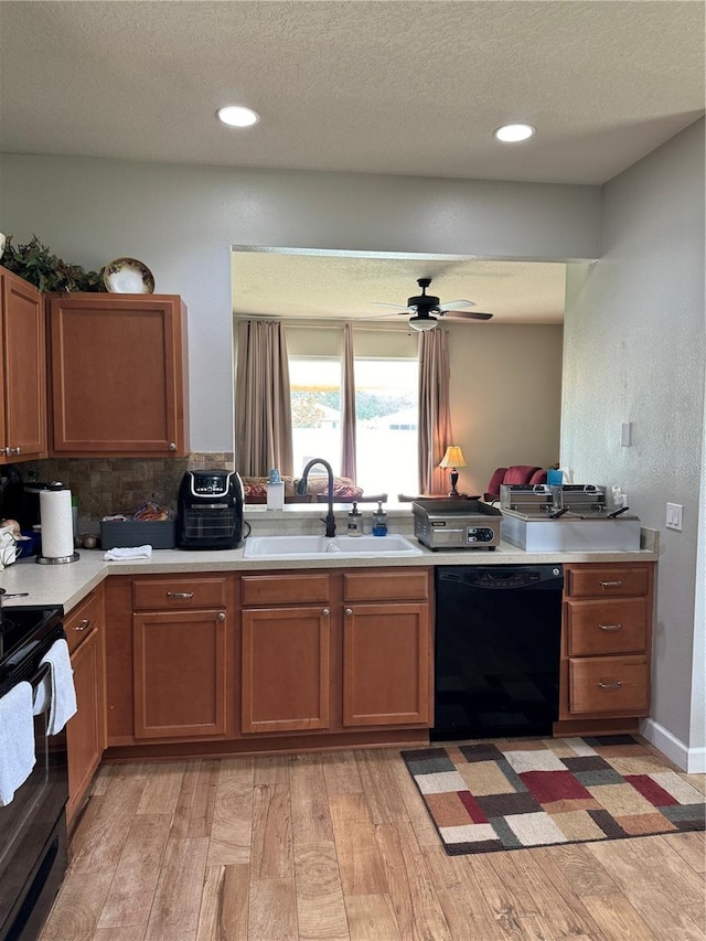 kitchen featuring kitchen peninsula, ceiling fan, light hardwood / wood-style floors, black appliances, and sink