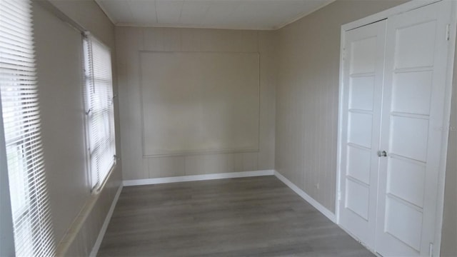 unfurnished room featuring plenty of natural light, wood finished floors, and baseboards