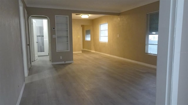 empty room featuring baseboards, a healthy amount of sunlight, and wood finished floors