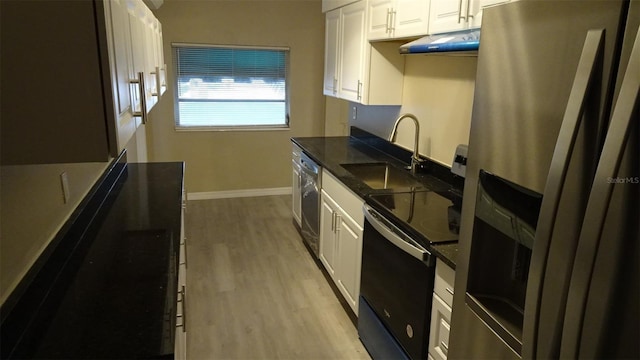 kitchen with under cabinet range hood, light wood-type flooring, white cabinets, stainless steel appliances, and a sink