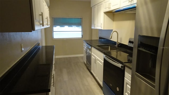 kitchen featuring light wood-style flooring, a sink, white cabinetry, stainless steel appliances, and baseboards