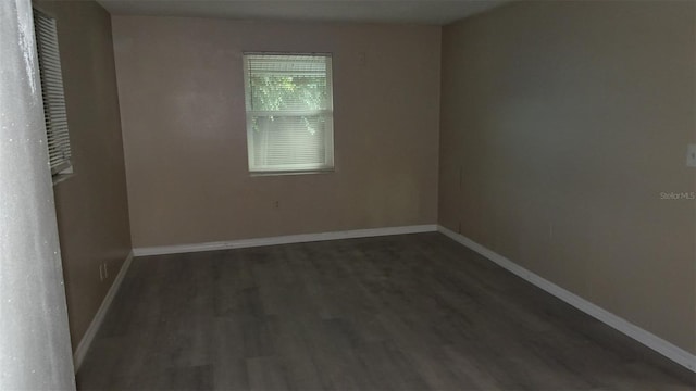 spare room featuring dark wood-style floors and baseboards